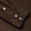 A dark brown shirt sleeve and cuff, three white buttons.