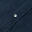 A navy corduroy fabric placket, with a white pearl button.