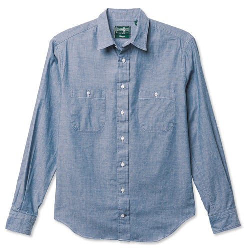 A blue work shirt with two chest pocket, made from a chambray fabric with white buttons.